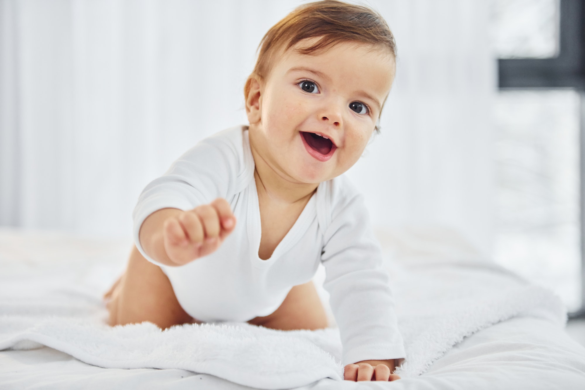 Playing on the bed. Cute little baby is indoors in the domestic room